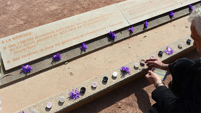 Homme allumant un lumignon au pied de la plaque commémorative
