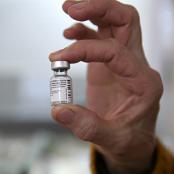 Personne âgée tenant une dose de vaccin entre ses doigts